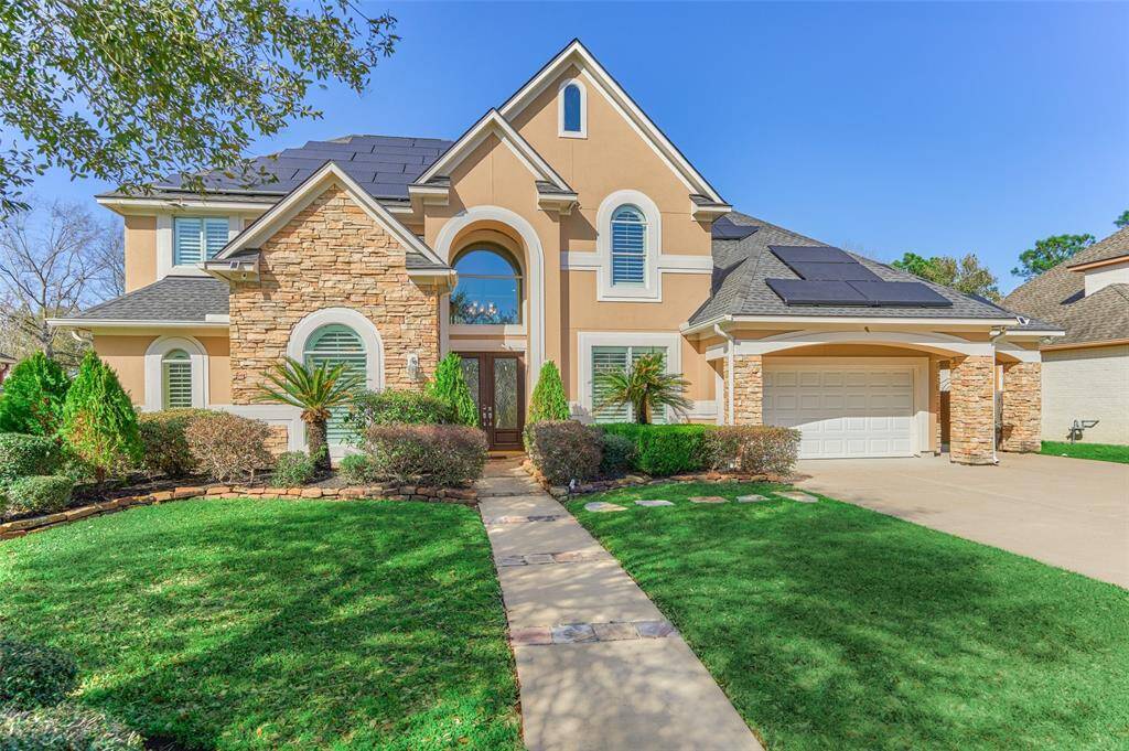 Stunning curb appeal with an elegant arched entry and eye-catching stacked stone facade, enhanced by stylish coach lighting.