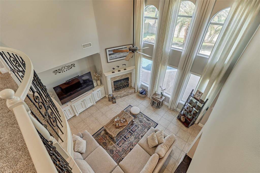 Bright living room with a cozy fireplace and large windows offering abundant natural light and views of the resort-style backyard.
