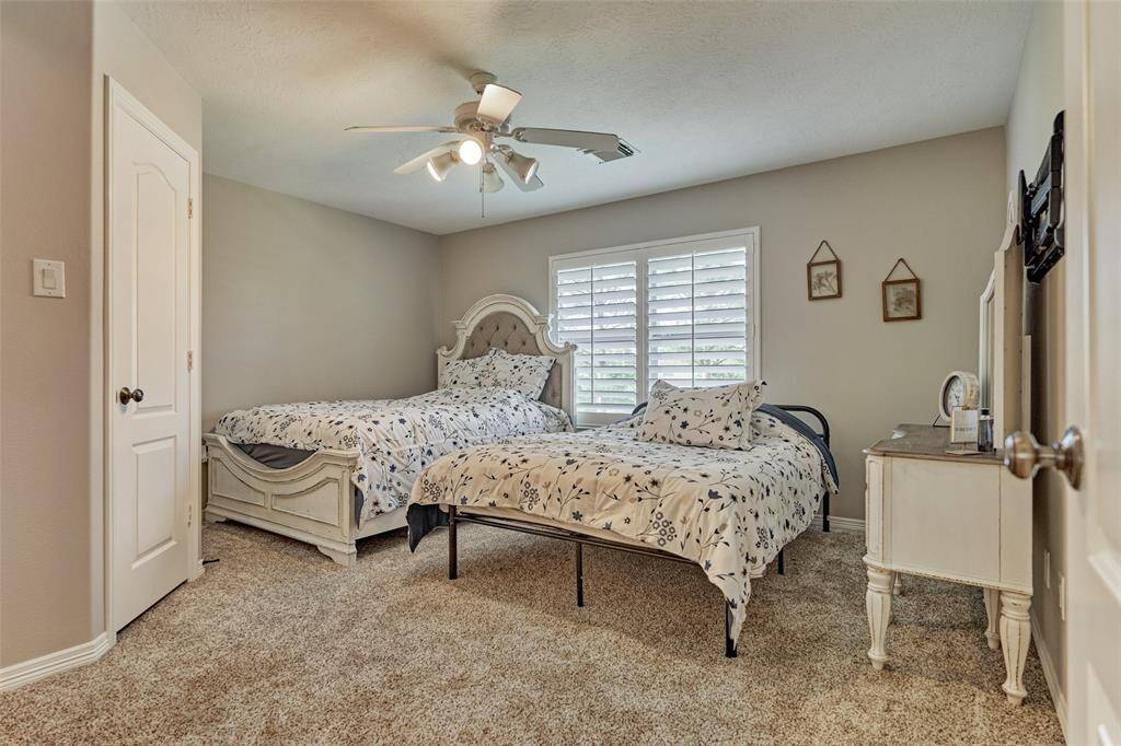 Expansive upstairs second bedroom with elegant plantation shutters.
