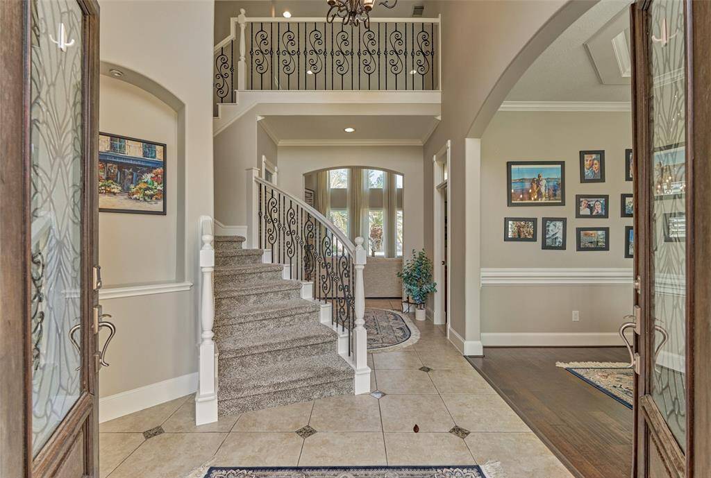 Welcome to a spacious foyer featuring a stunning wrought iron staircase. To the left, find a cozy study; to the right, a formal dining room awaits.