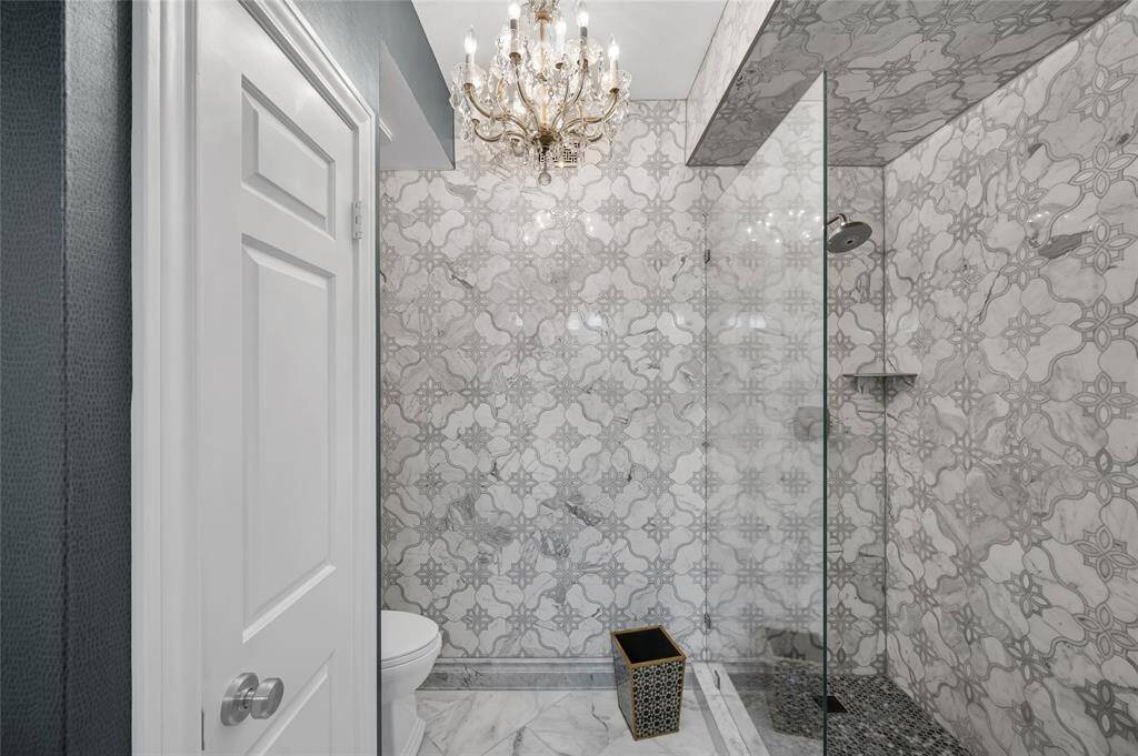 This stunning walk-in shower combines modern design with timeless elegance. A statement chandelier adds a touch of luxury, casting a warm and inviting glow.