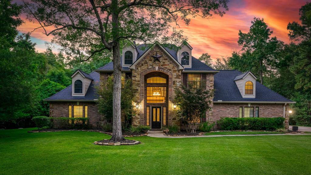 Front of the Dunn and Stone house with brick and stone exterior. This gorgeous country estate is surrounded by trees. This is a one of a kind property!