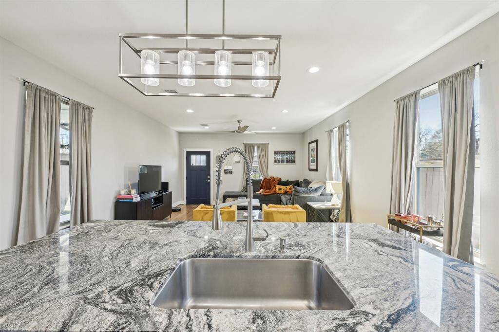 This bathroom features a modern design with a white vanity and vessel sink, a large mirror, and a toilet. There's cabinetry above the toilet for extra storage and a towel ring with a blue towel, all set against a neutral wall.