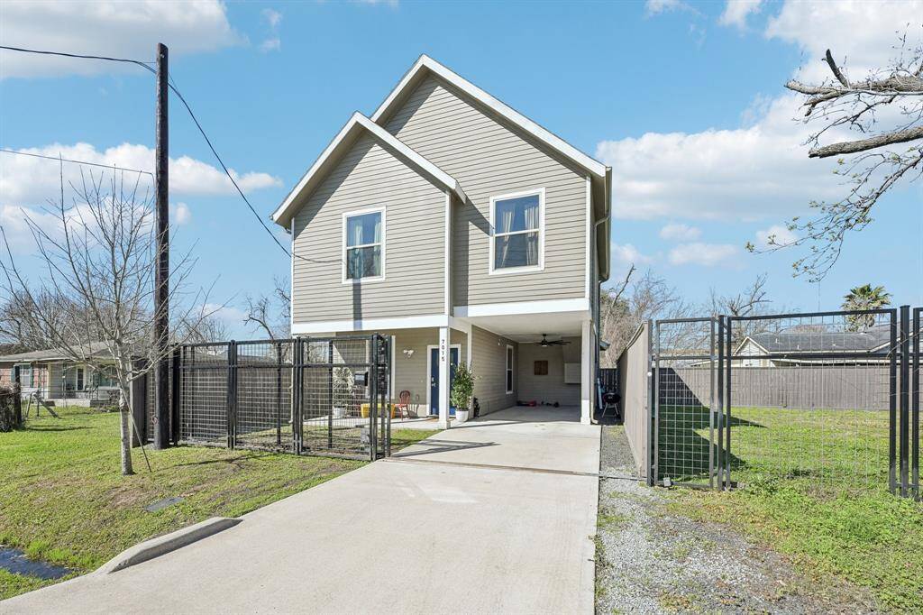 This modern two-story home features a sleek exterior with neutral siding, large windows, and a private fenced yard. The property offers ample outdoor space and is complemented by mature trees, providing a serene and inviting atmosphere.