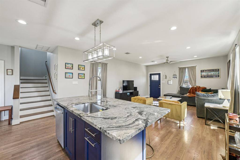 Bright, open-concept living space with hardwood floors, modern kitchen, and ample natural light. Features a cozy seating area, island with barstools, and stainless steel appliances. Ideal for entertaining and family gatherings.