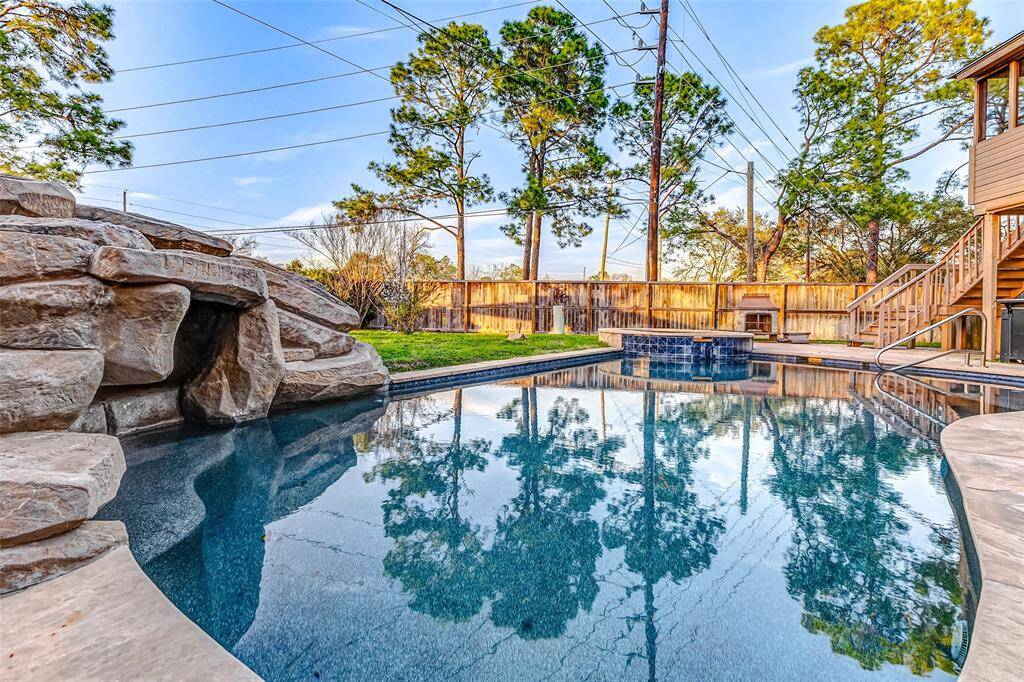 heated pool with a waterfall and hot tub