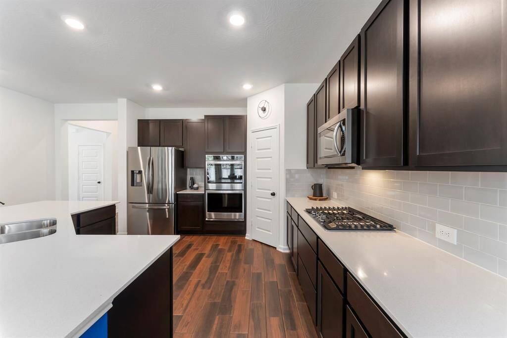 The kitchen is beautifully appointed with 42” maple shaker-panel cabinets, elegant Silestone countertops, and a classic subway tile backsplash, creating a timeless aesthetic. Energy Star stainless steel appliances elevate the space, including double ovens with a touch screen, a built-in microwave, a 30” 5-burner gas cooktop with griddle and Samsun double-door refrigerator that stays with the home.