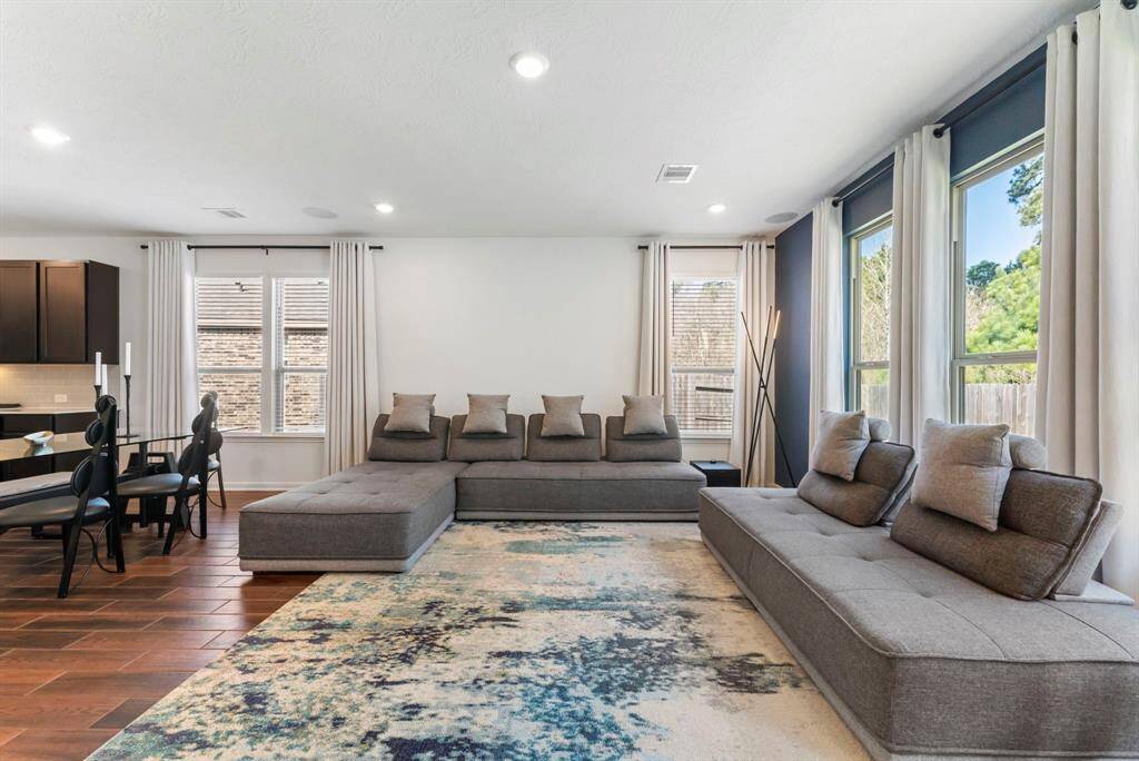 The space is light and bright, enhanced by recessed lighting and a striking wall of windows that floods the home with natural light.