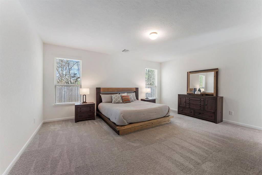 The large primary bedroom offers a spacious and luxurious feel, with high ceilings, plush carpet and neutral paint.