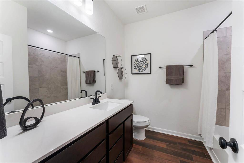 A full bath is located between the secondary bedrooms featuring an enlarged vanity with Silestone counters, wood-like tile flooring and shower/tub combination.