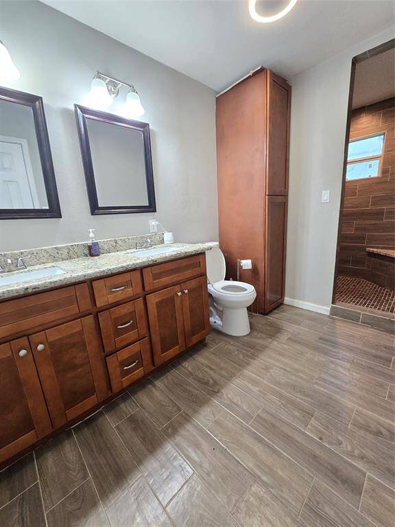 Primary Bathroom features a double-sink vanity with granite countertops and wooden cabinets.