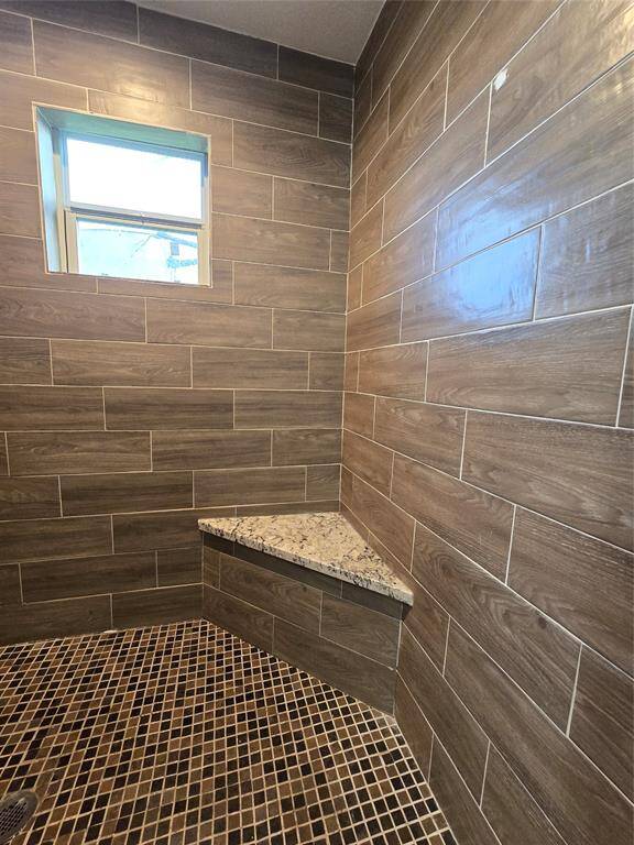Spacious primary walk-in shower featuring convenient bench seating for relaxation and comfort.