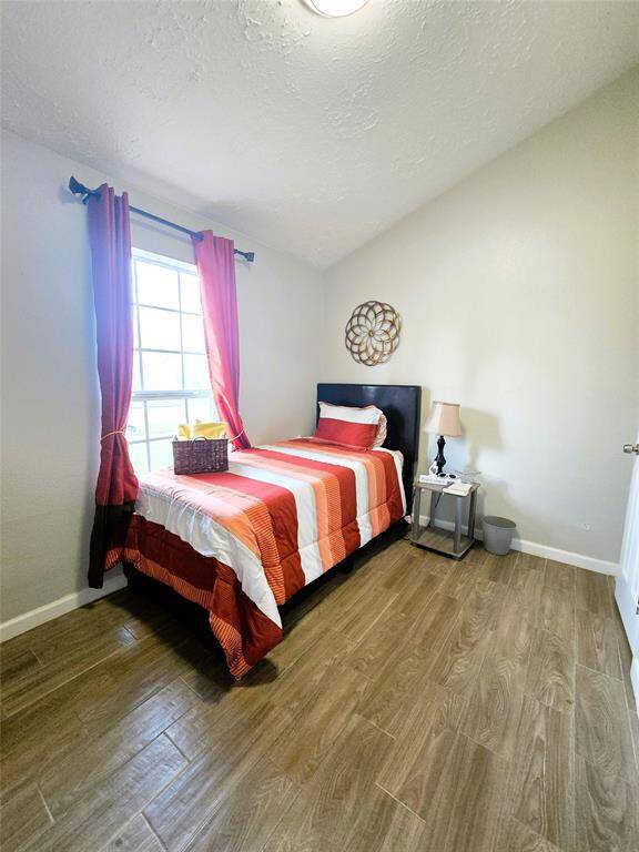 Second Bedroom features large window allowing natural light to brighten the space and wood-style flooring.