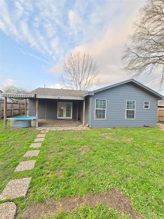 Spacious backyard features a covered patio and French doors. The space is fully fenced, offering privacy. NO BACK NEIGHBORS!
