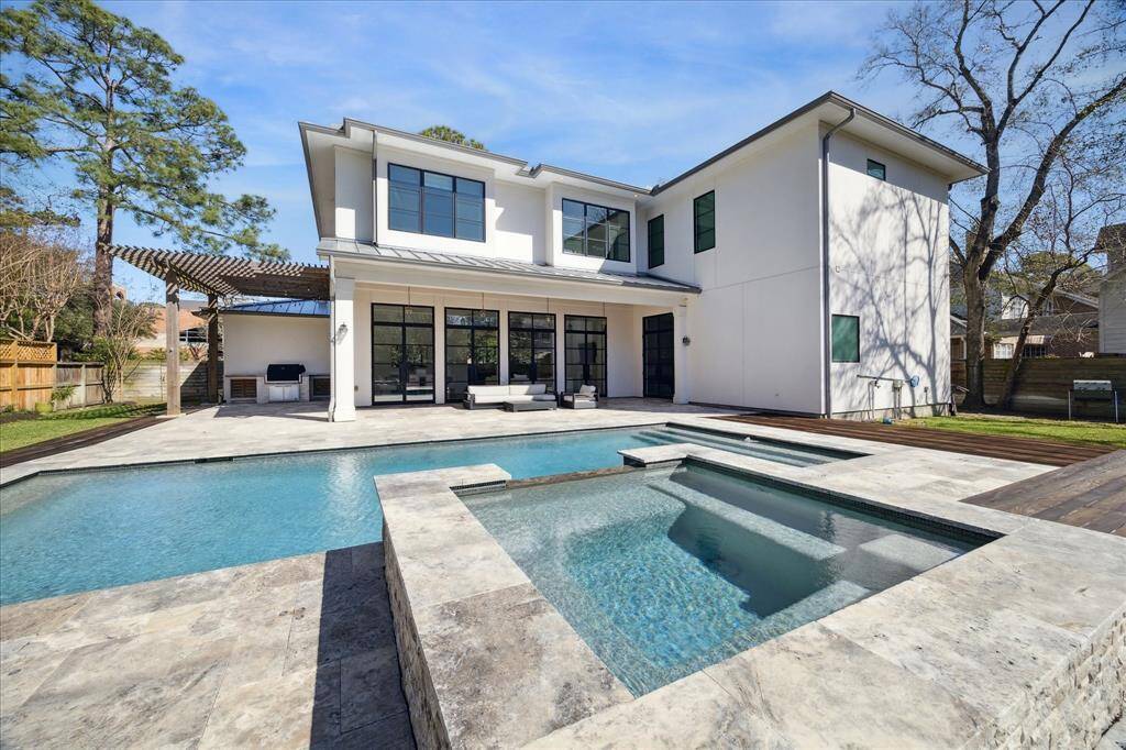 Designed for entertaining, the home offers a seamless flow to the outdoors, where a covered veranda, pergola-shaded summer kitchen, and resort-style pool with spa and water features create a private oasis.