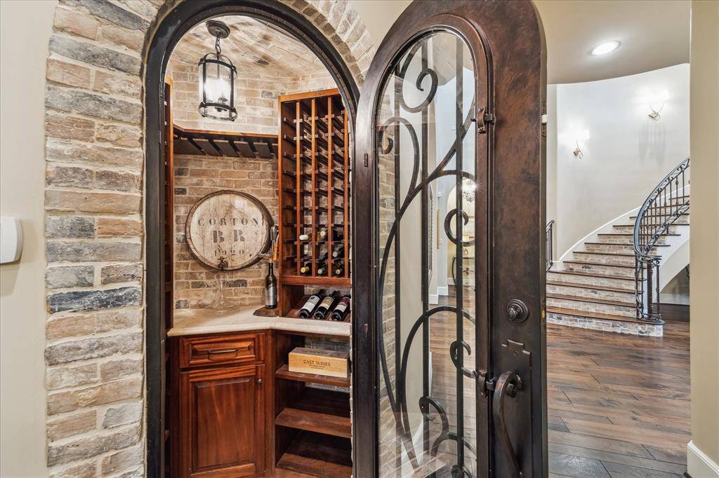 Climate controlled wine celler with wrought iron door featuring wine display rack and brick walls.