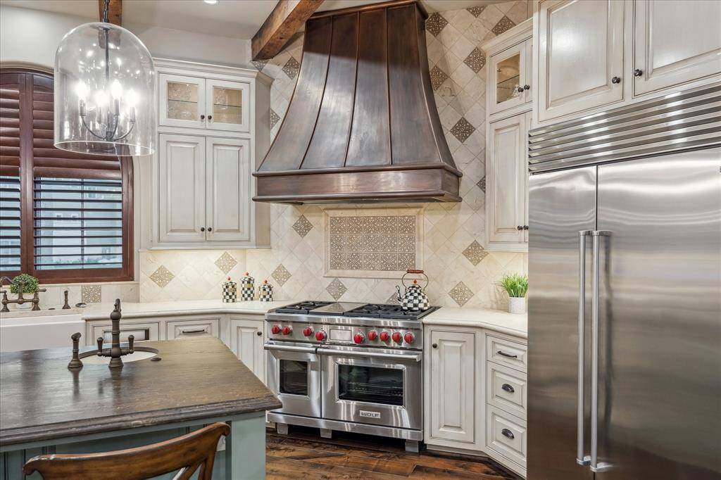 Appliance package includes a Subzero refrigerator and Wolf range with six burners, double oven and griddle with a custom range hood.