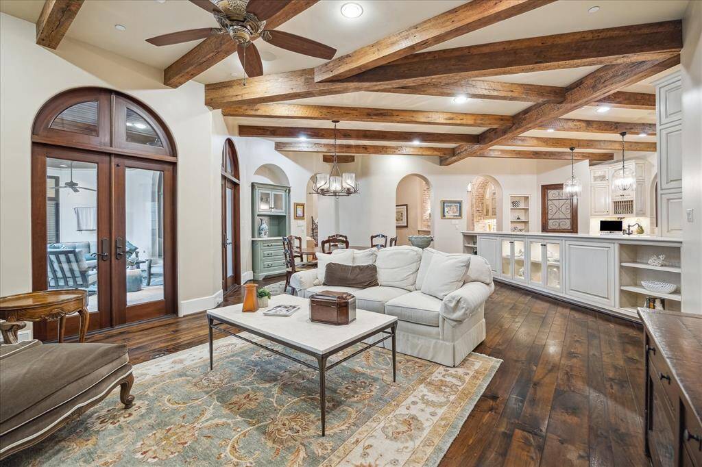 The family room features exposed wooden beams and arched double French doors that open to the backyard, creating a seamless flow.