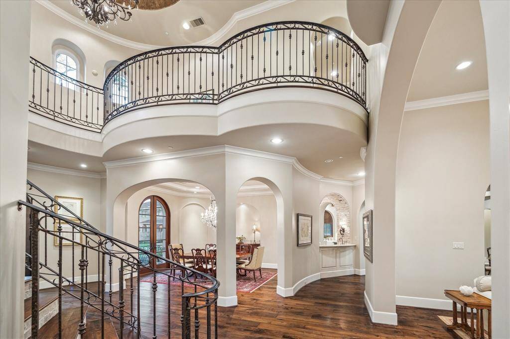 Luxurious grand curved staircase featuring decorative iron railing.