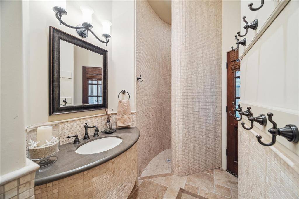 Outdoor full bath, designed for poolside convenience, features a stylish and functional layout.