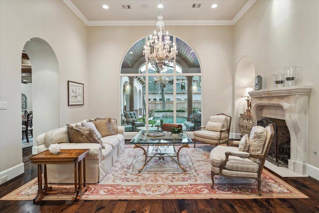 The formal living room features a grand arched window, offering a breathtaking view of the backyard and abundant natural light.
