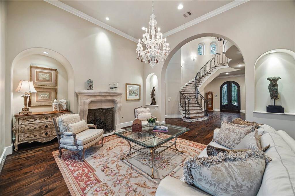 The formal living room boasts arched doorways, crown molding, a beautiful chandelier, and a cozy gas fireplace.
