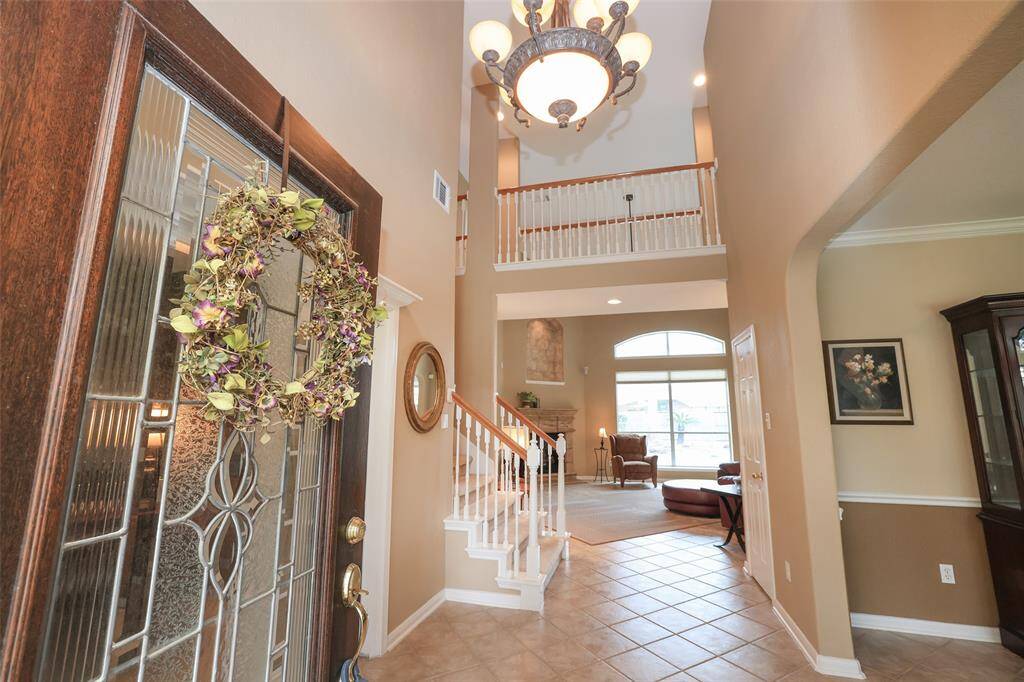 Two story entry foyer with chandelier and tiled flooring.Neutral paint. Crown molding.