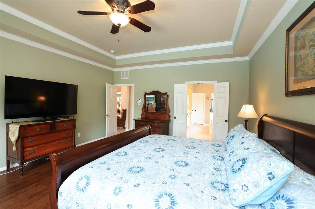 Primary bedroom on main level with wood floors and double crown molding. Full wall of windows.