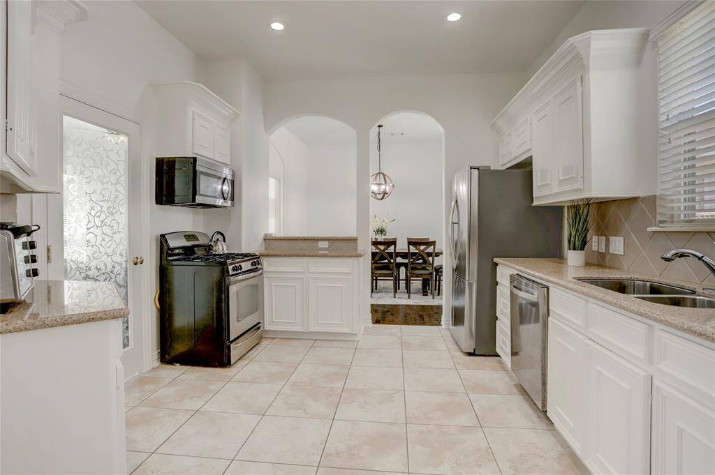 The gourmet kitchen boasts granite countertops, stainless steel appliances, a gas range, custom cabinetry, and a breakfast bar.
