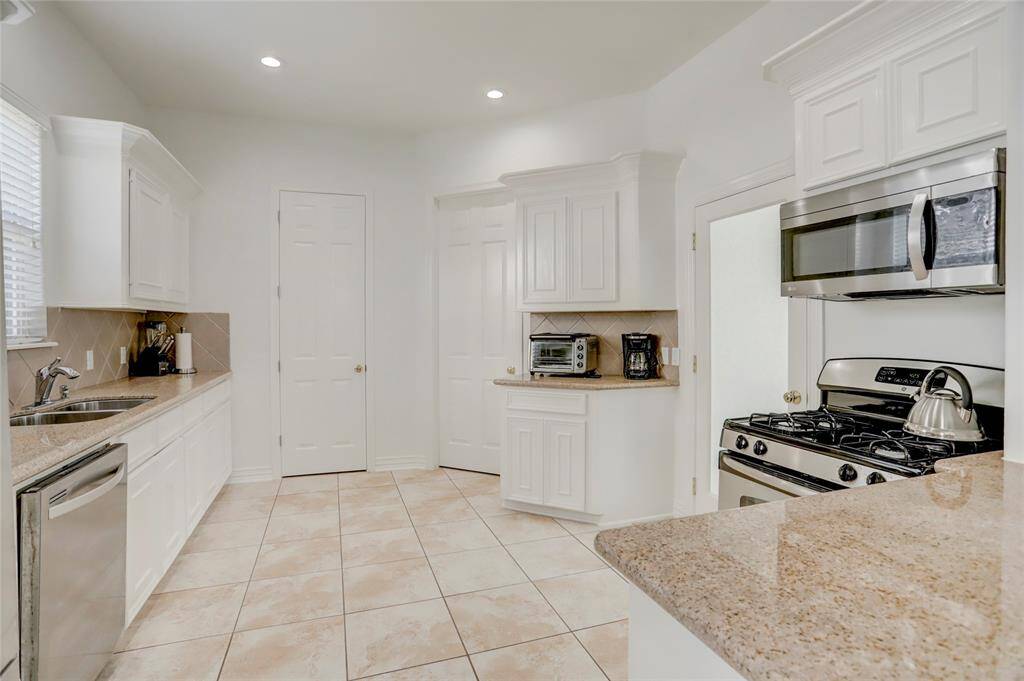 Another angle of the kitchen, featuring a tile backsplash, ample storage, and a functional design for effortless meal prep.