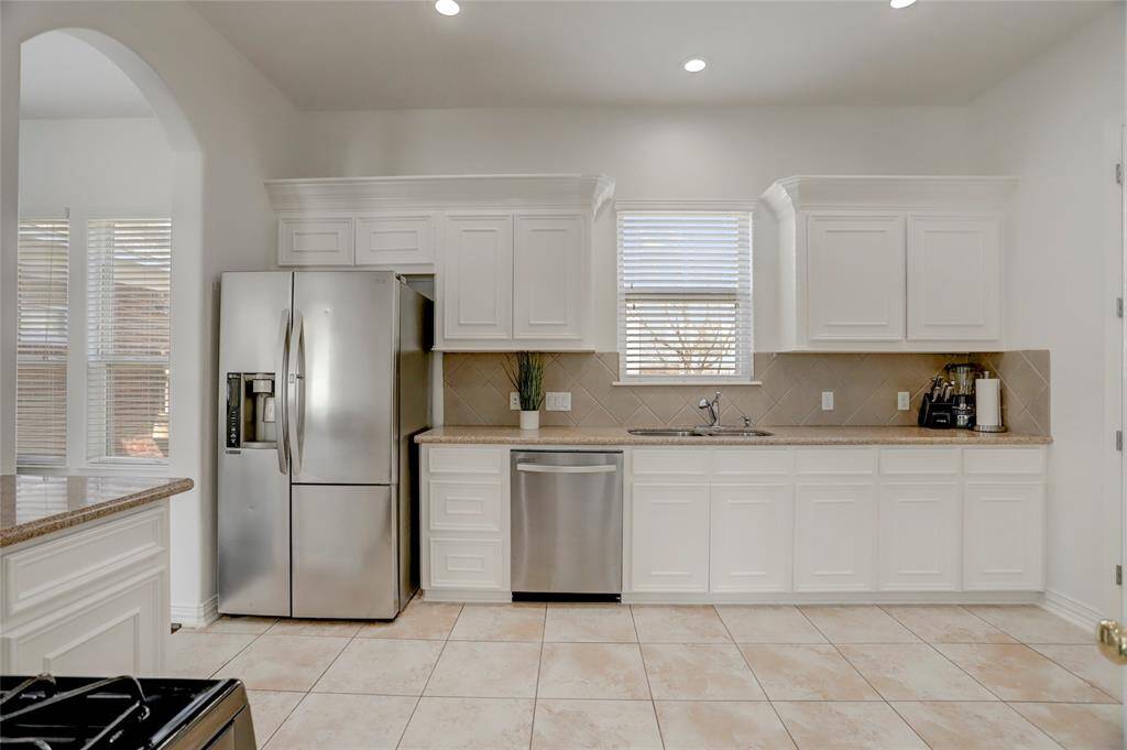 The gourmet kitchen features sleek stainless steel appliances and a  window that bathes the space in natural light, creating a bright and inviting atmosphere. Perfect for both cooking and entertaining, it seamlessly blends style and functionality.