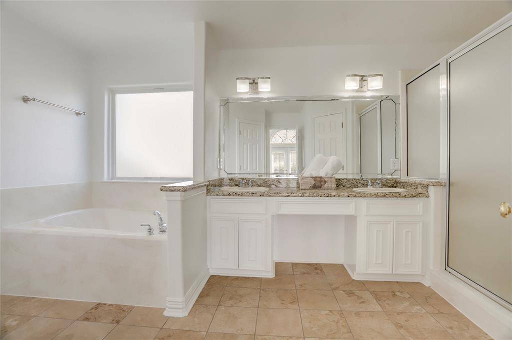 A luxurious ensuite bath with double sinks, a soaking tub, a separate glass-enclosed shower.