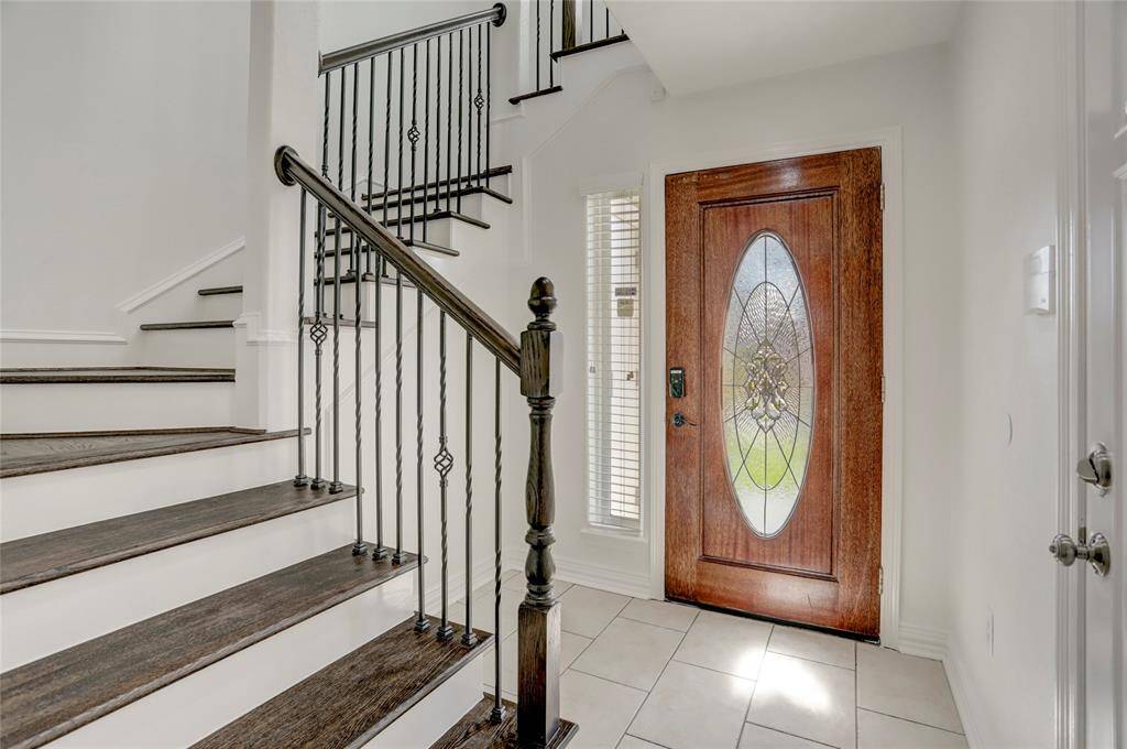 A welcoming foyer with elegant tile flooring, a sleek wood-accented front door, and stylish lighting setting the stage for a refined interior.