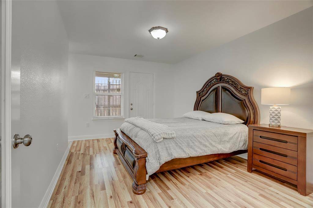 A bright and airy bedroom with rich wood flooring, a large window for natural light, and ample space for versatile use.