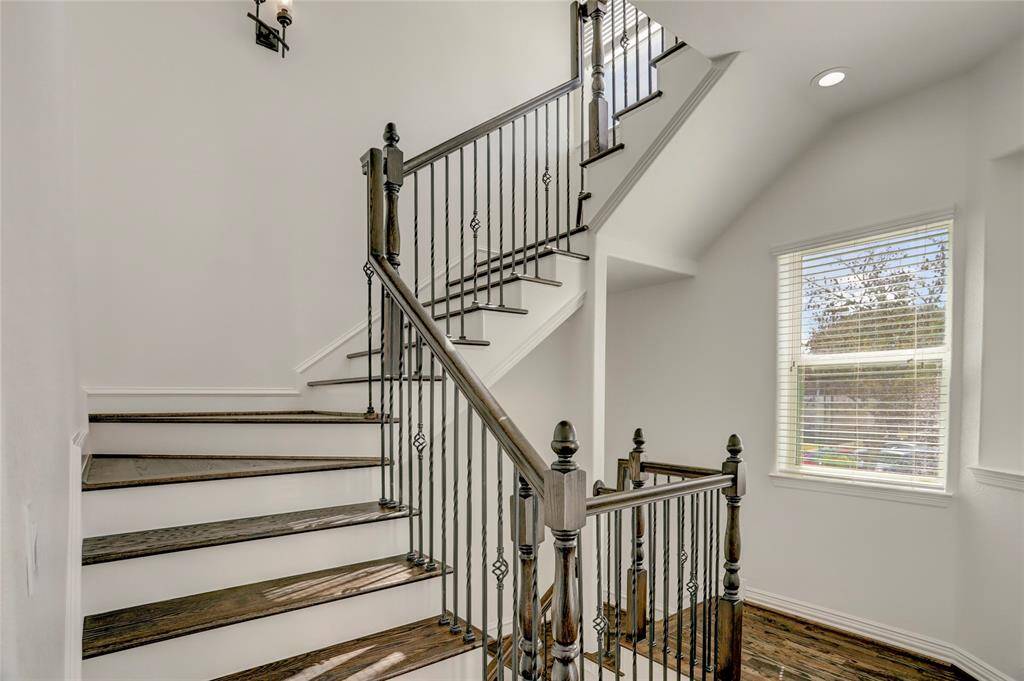 A grand staircase with wrought iron railings and dark wood steps adds a sophisticated touch while seamlessly connecting all three levels.