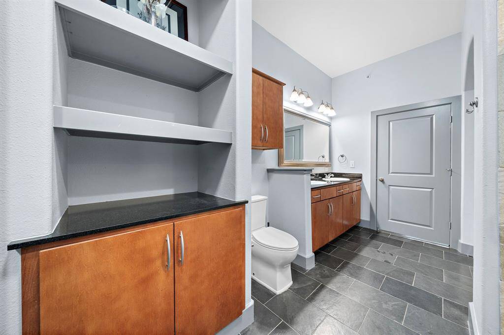 This well-appointed bathroom features rich wood cabinetry and sleek black countertops, creating a stylish and functional space.