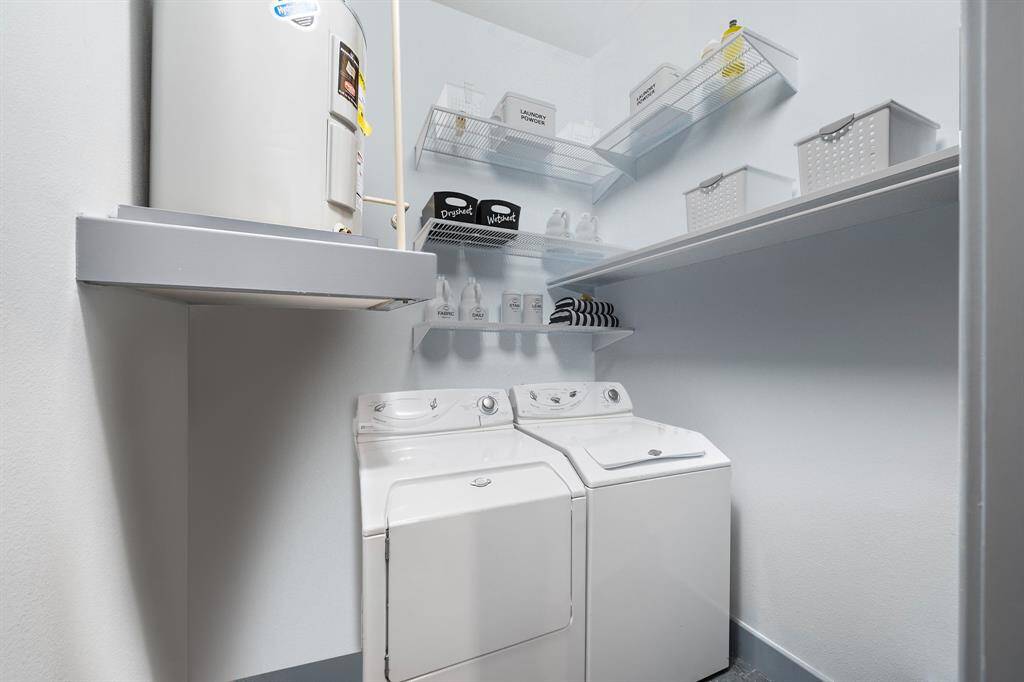 Efficient and practical, this well-organized laundry room features a stacked washer and dryer unit with wall-mounted shelving for ample storage.
