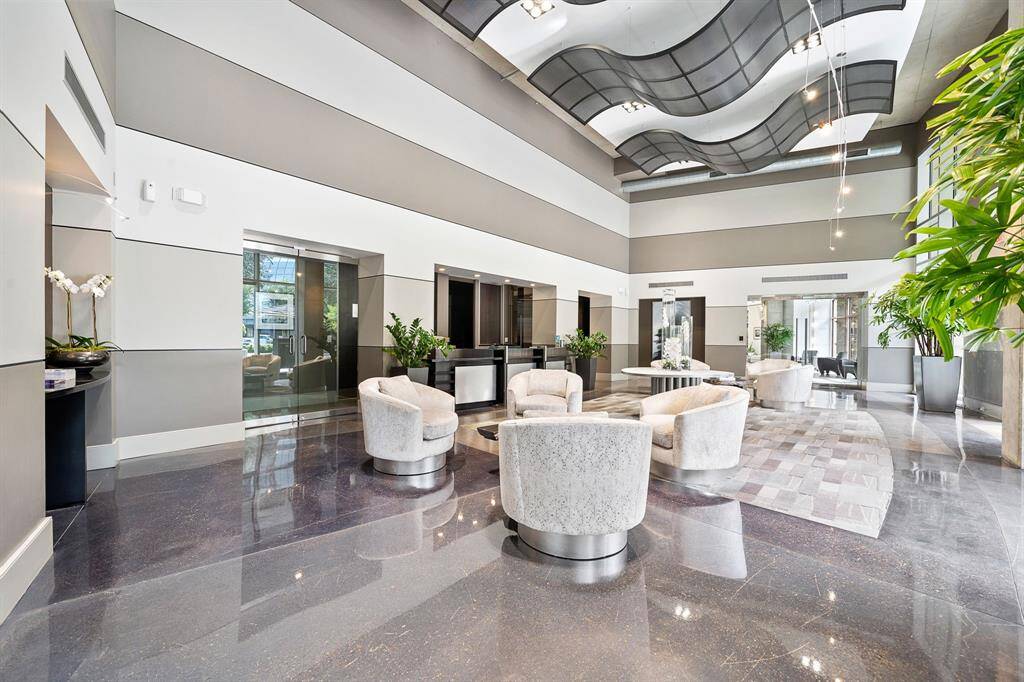 The sophisticated lobby showcases a striking wave-patterned ceiling and polished stone floors, complemented by plush circular seating creating an elegant and inviting atmosphere for residents and guests alike.