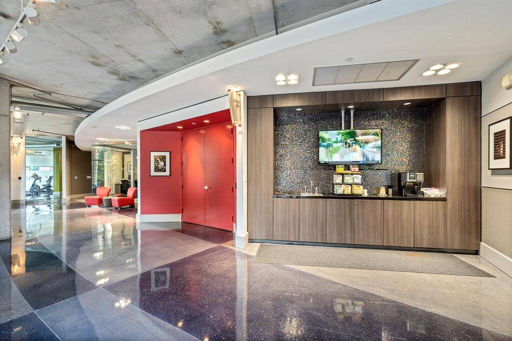 Discover the chic common area featuring an elegant coffee bar with sleek cabinetry, mosaic tile backdrop, and a mounted TV for entertainment.