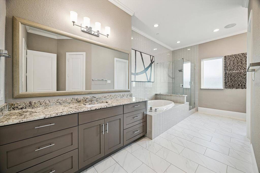 Tasteful primary bathroom featuring elegant Quartzite countertops, a spacious vanity, and a relaxing soaking tub with a separate glass-enclosed shower.
