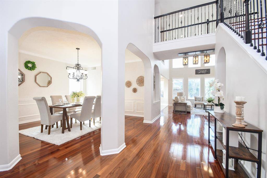 View from the entrance door showing a spacious, two-story foyer, grand stairs and a two-story living room
