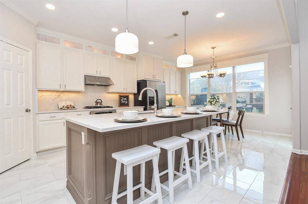 The kitchen is completely remodeled with quartz islands and matching quartz backsplash, refinished cabinets, and newly tiled floors.