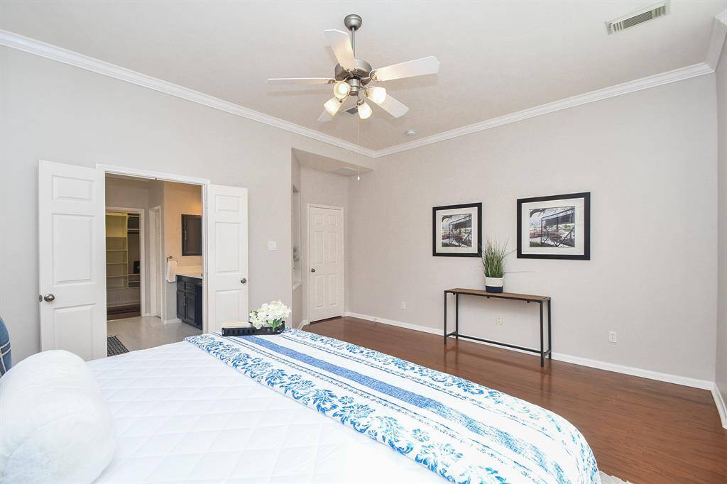 Another view of the primary bedroom showing the entrance to the primary bathroom and ample space for a large dresser