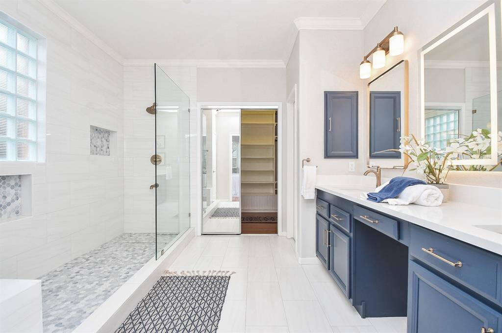 This bathroom features a spacious walk-in shower with glass doors and a sleek tile design along with a bench.