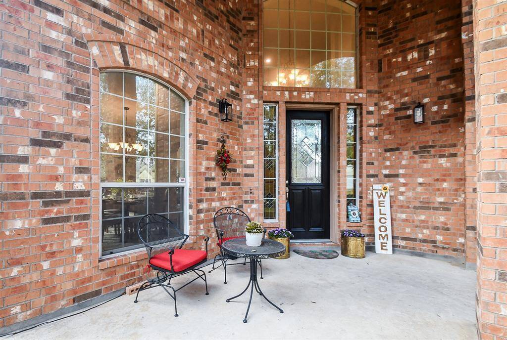 The front porch is all brick with a large window above the freshly stained door and enough room for a seating area