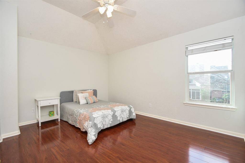 This large-0size secondary bedroom features a high ceiling with a fan, a large window providing natural light.