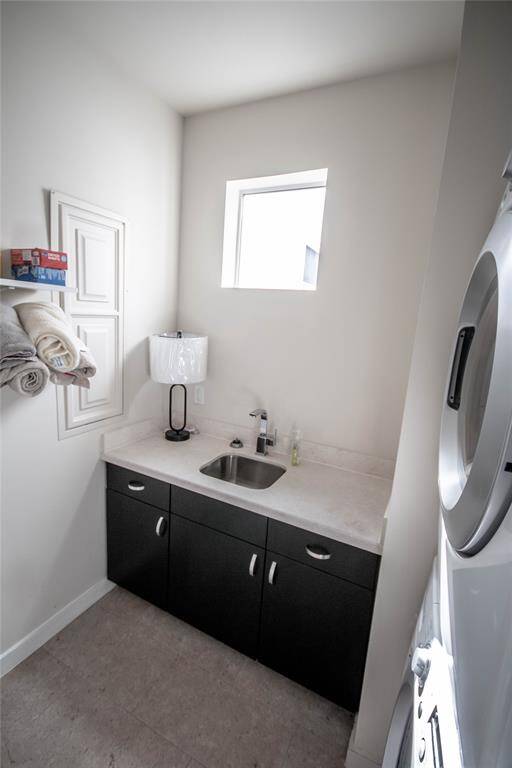 Laundry on third floor with a sink and stack washer and dryer