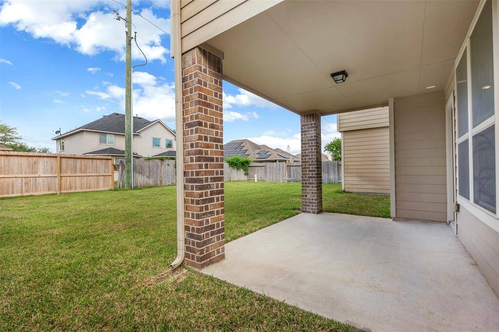 This listing features a spacious yard, a covered patio, and a brick exterior.