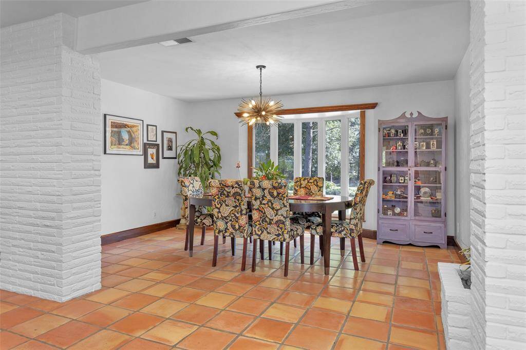 This home is full of character at every turn, with brick accent walls, a midcentury modern chandelier, bay windows, crown molding, and wood beams.