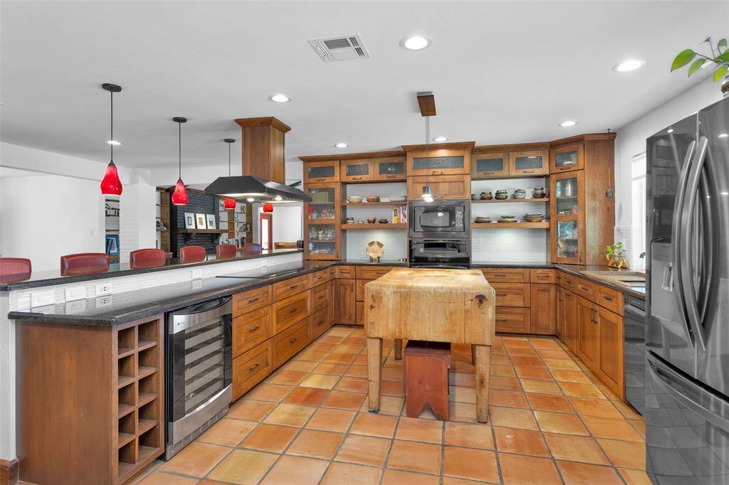 The custom Amish-built wood cabinetry, featuring a blend of open shelves, glass-front doors, drawers, and unique corners, makes this kitchen a dream for any cook. With a double oven, electric cooktop, wine fridge, and oversized copper sink, it has all the essentials. (The butcher block island is not included in the sale.)